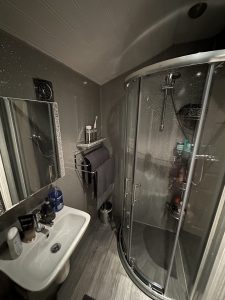 Photo of a slate grey bathroom installation with a basin and chrome shower cubicle visible.