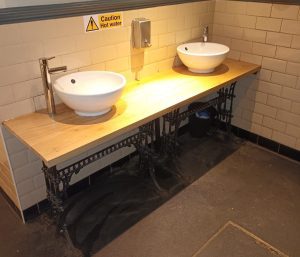 A photo of a pub toilets hand wash basins on a pale oak unit.
