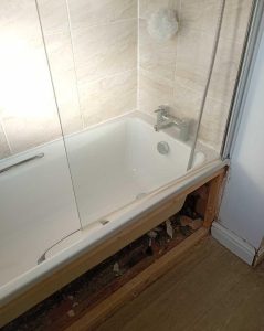 Bath leak repair with panel removed for pipe access.