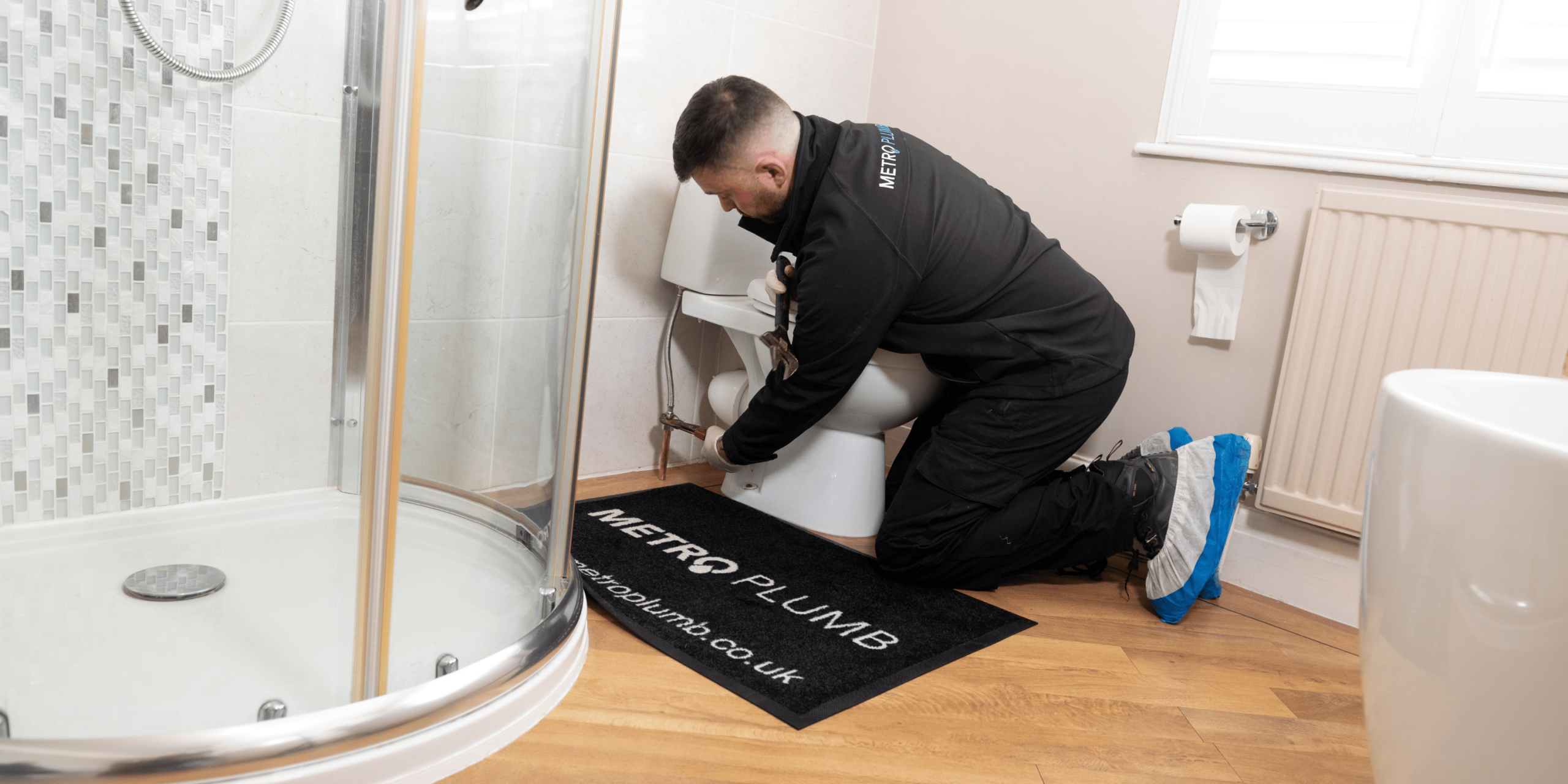 Bathroom installer fitting a toilet in a modern bathroom during a professional bathroom installation.