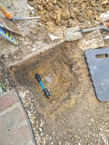 Small excavated section exposing underground water pipe for targeted leak repair.